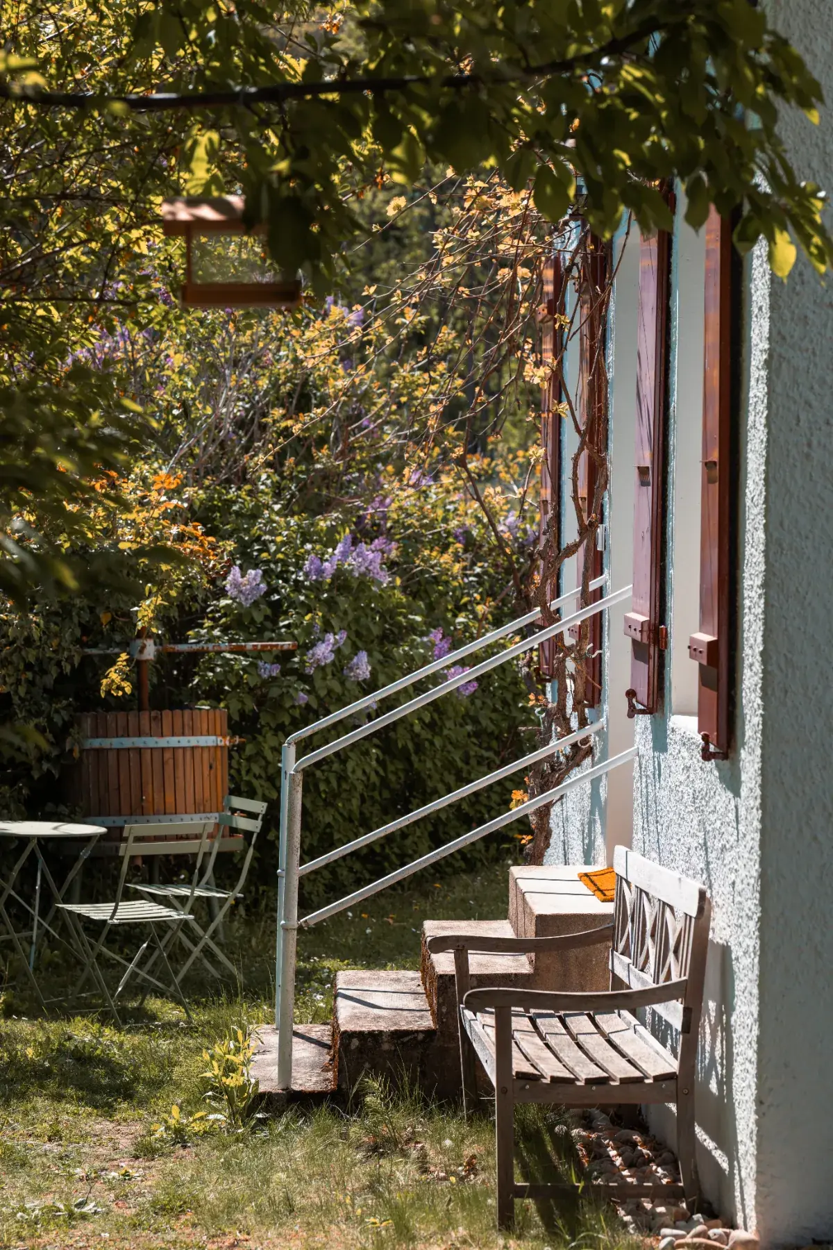 Escalier extérieur et banc en bois du Cabanon des Vignes au milieu de la verdure