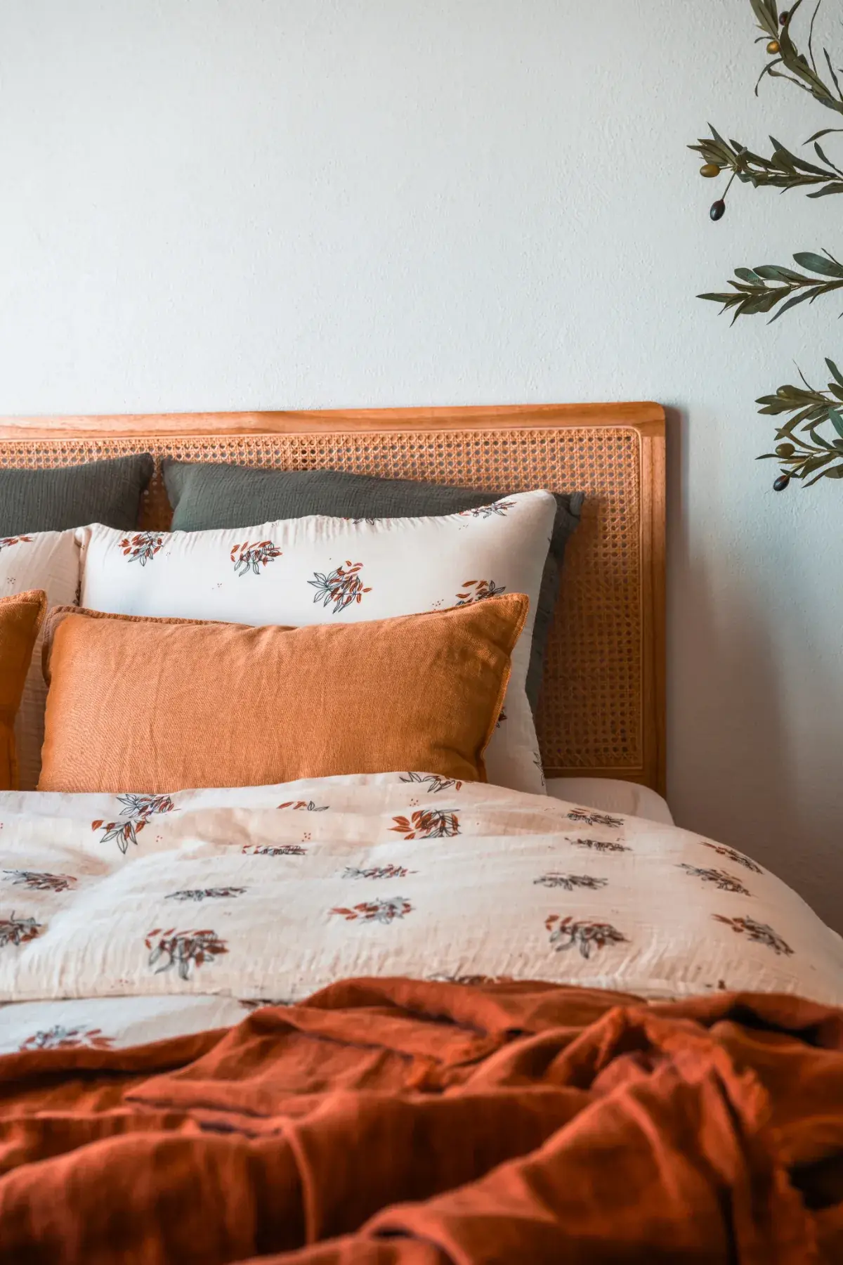 Lit double avec coussins et plaid orange dans le Cabanon des Vignes